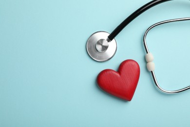Photo of Stethoscope and red heart on light blue background, top view. Space for text
