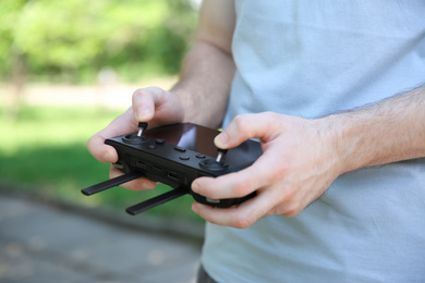 Photo of Man holding new modern drone controller outdoors, closeup of hands