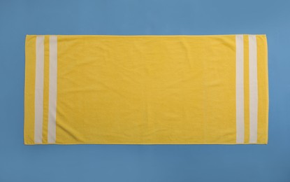 Photo of Yellow beach towel on blue background, top view