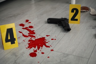 Photo of Crime scene markers, gun and blood on floor