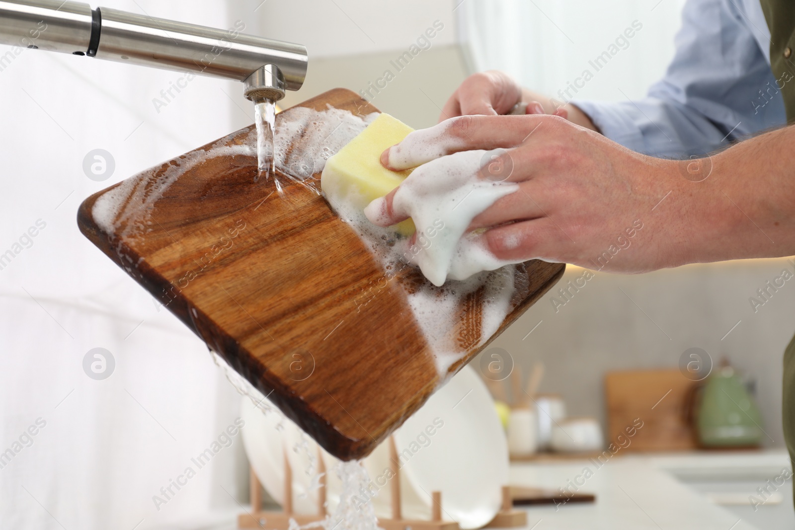 Man washing wooden cutting board in kitchen, closeup Photo of Man washing wooden cutting board in kitchen, closeup