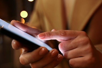 Photo of Woman using smartphone on blurred background, closeup