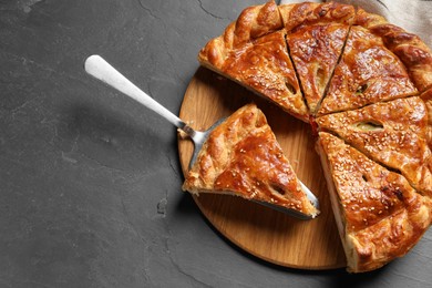 Photo of Cut delicious homemade pie and server on black table, top view