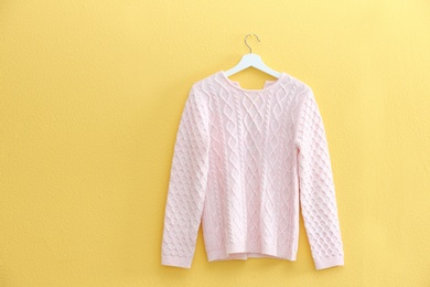Photo of Hanger with stylish sweater on yellow wall