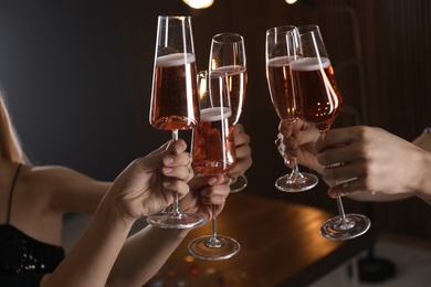 Photo of Friends clinking glasses with champagne on blurred background, closeup