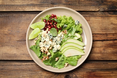 Photo of Fresh salad with pear on wooden table, top view