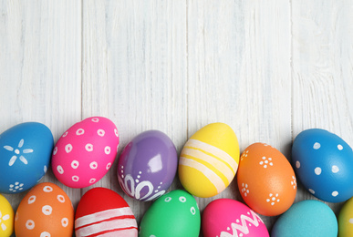 Photo of Many bright Easter eggs on white wooden background, flat lay. Space for text