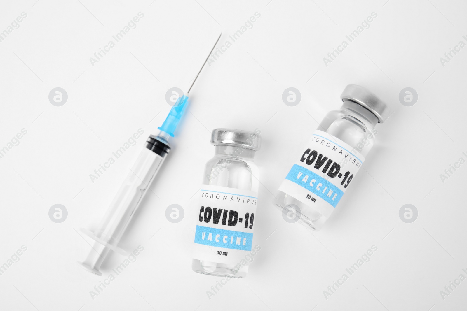 Photo of Vials with coronavirus vaccine and syringe on white background, flat lay
