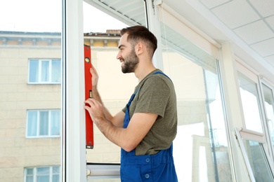 Photo of Construction worker using bubble level while installing window indoors