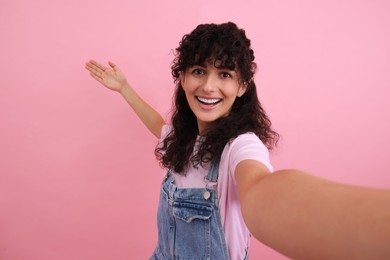 Beautiful woman taking selfie on pink background