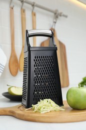 Photo of Grater and fresh ripe apple on kitchen counter