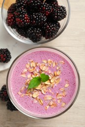 Photo of Delicious blackberry smoothie with oatmeal and berries on white wooden table, flat lay