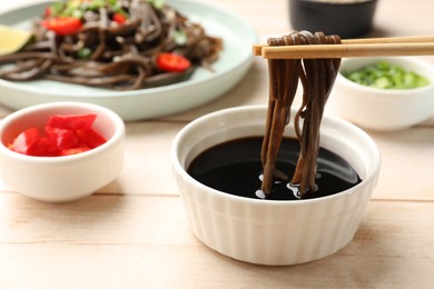 Photo of Eating delicious buckwheat noodle (soba) soup with chopsticks at white wooden table, closeup