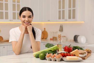 Photo of Happy woman with different products in kitchen. Keto diet