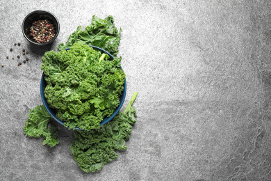 Fresh kale leaves and pepper on grey table, flat lay. Space for text