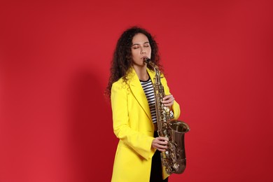 Photo of Beautiful African American woman playing saxophone on red background