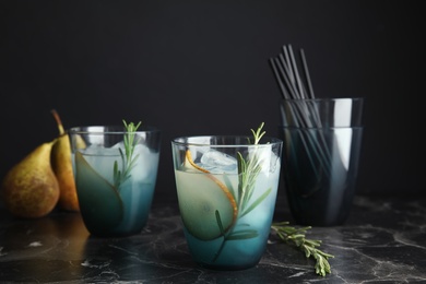 Photo of Tasty refreshing pear cocktail with rosemary on table