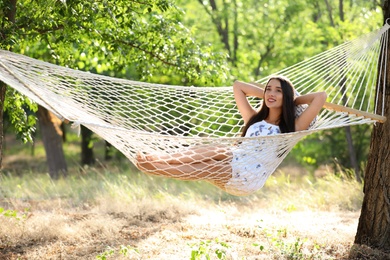 Photo of Young woman resting in comfortable hammock at green garden