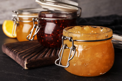 Photo of Delicious homemade jams on black wooden table