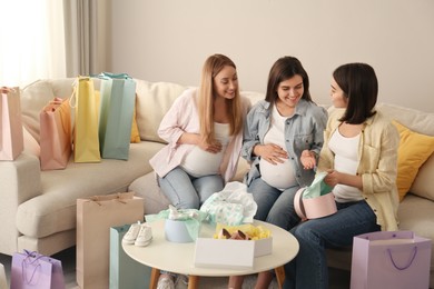 Photo of Happy pregnant women spending time together in living room after shopping