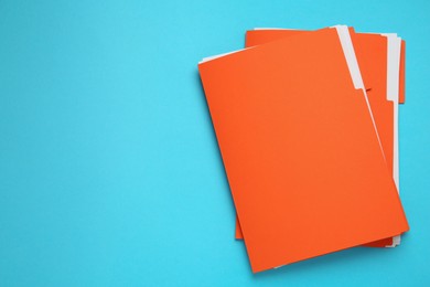 Photo of Orange files with documents on turquoise background, top view. Space for text