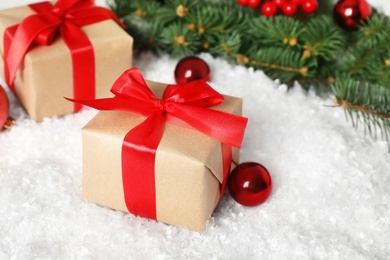 Photo of Christmas gift box and decor on table with artificial snow, closeup
