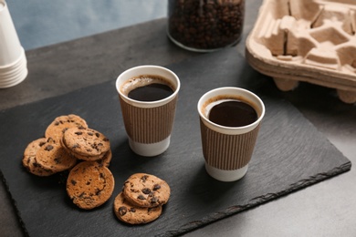 Photo of Composition with aromatic hot coffee in paper cups and cookies on table