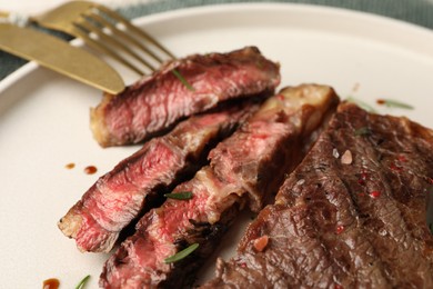 Photo of Delicious grilled beef steak with spices on plate, closeup