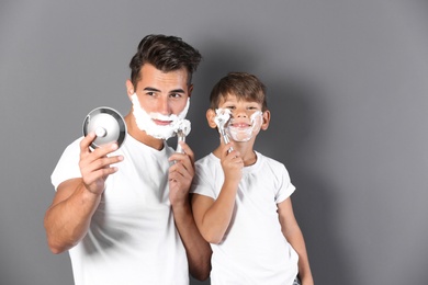 Photo of Father and son shaving on color background