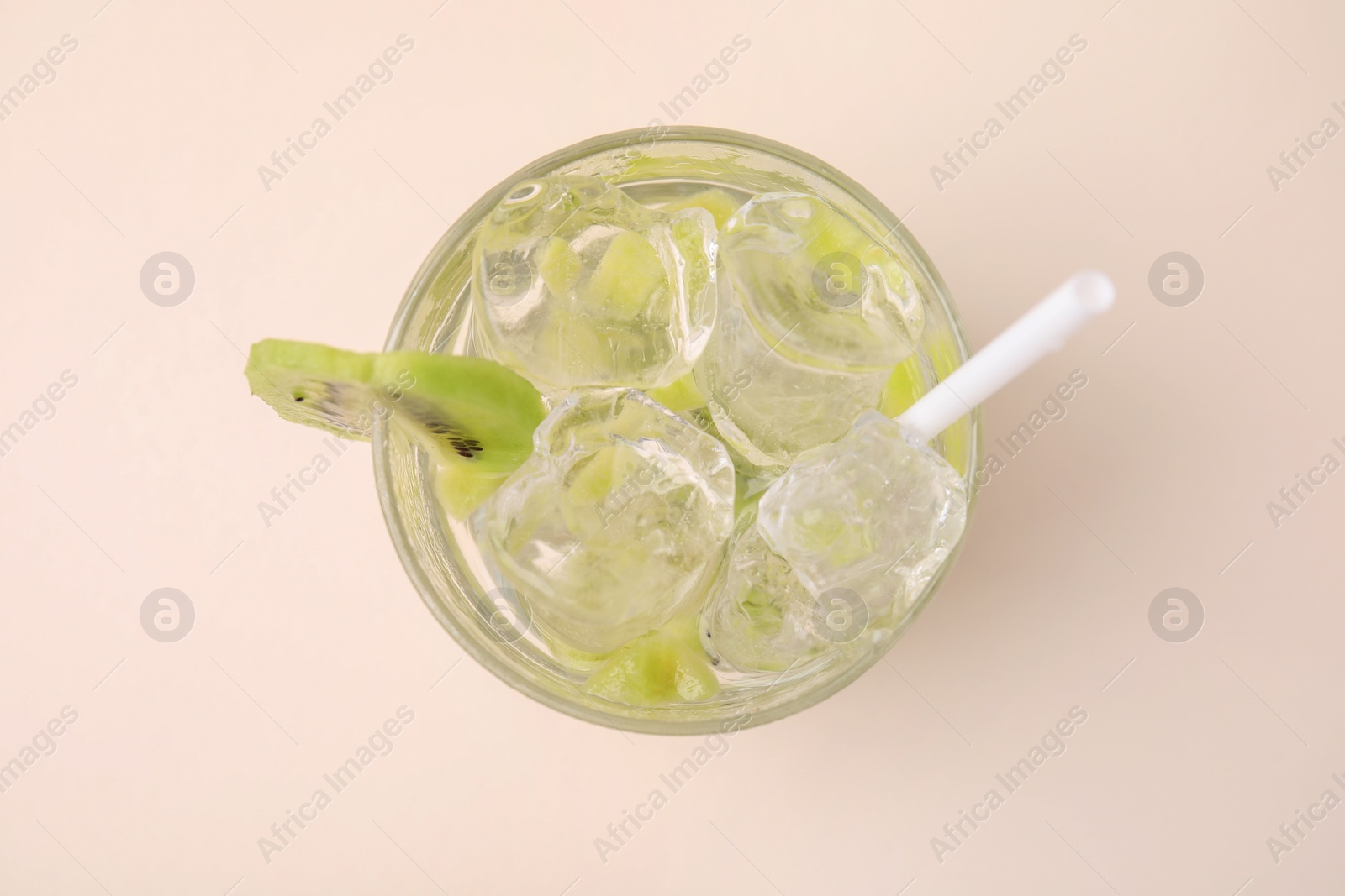 Photo of Glass of refreshing drink with kiwi on beige background, top view