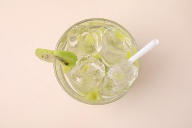Photo of Glass of refreshing drink with kiwi on beige background, top view