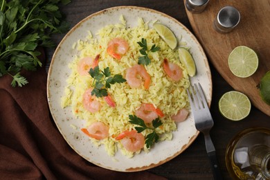 Photo of Delicious risotto with shrimps, lime and parsley served on wooden table, flat lay