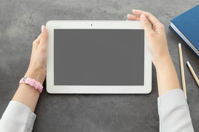 Photo of Woman holding tablet with blank screen at table. Mockup for design