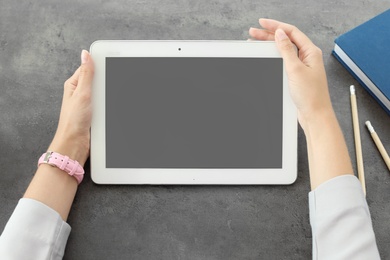 Woman holding tablet with blank screen at table. Mockup for design