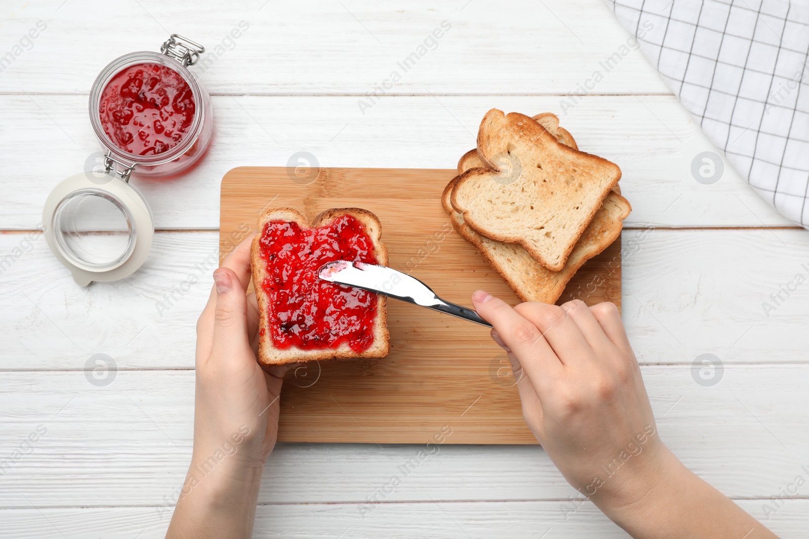 Photo of Woman spreading jam on toast against wooden background