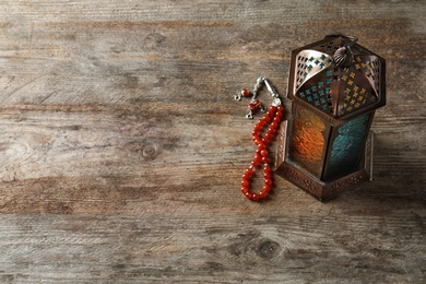 Muslim lamp and misbaha on wooden background. Fanous as Ramadan symbol