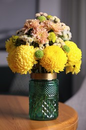 Photo of Bouquet of beautiful chrysanthemum flowers on wooden table indoors