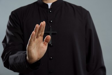 Photo of Priest making blessing gesture on grey background, closeup
