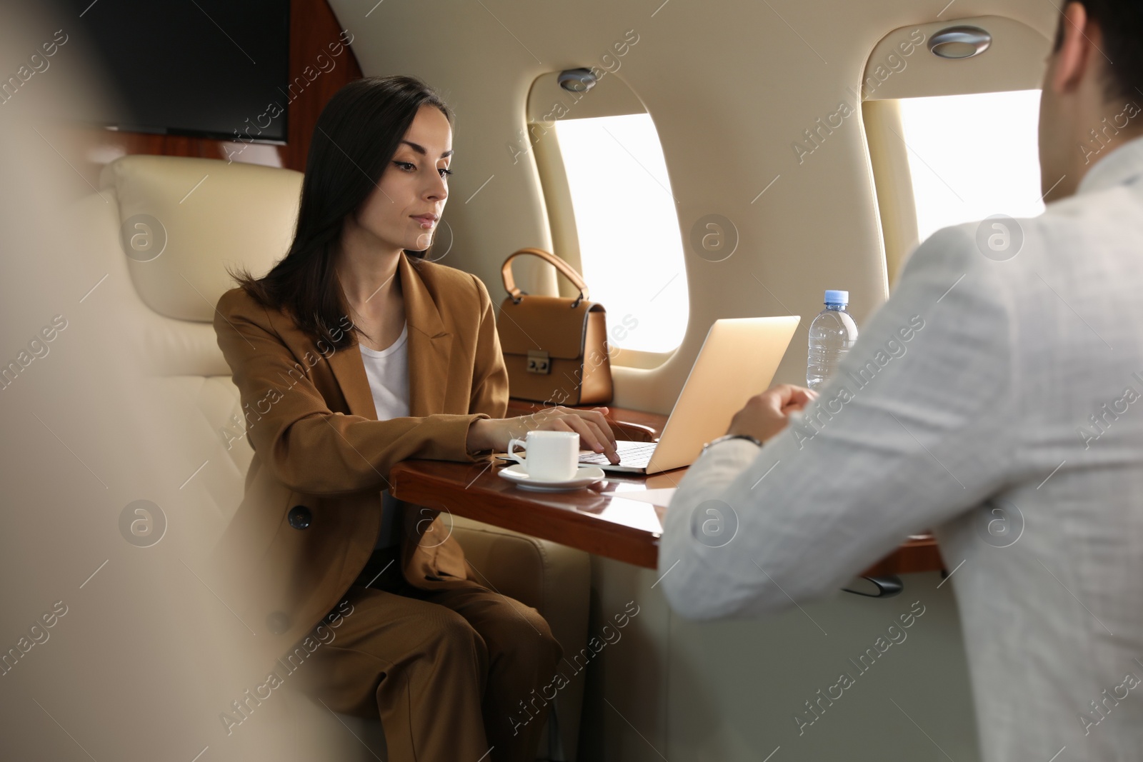 Photo of Colleagues working at table in airplane during flight