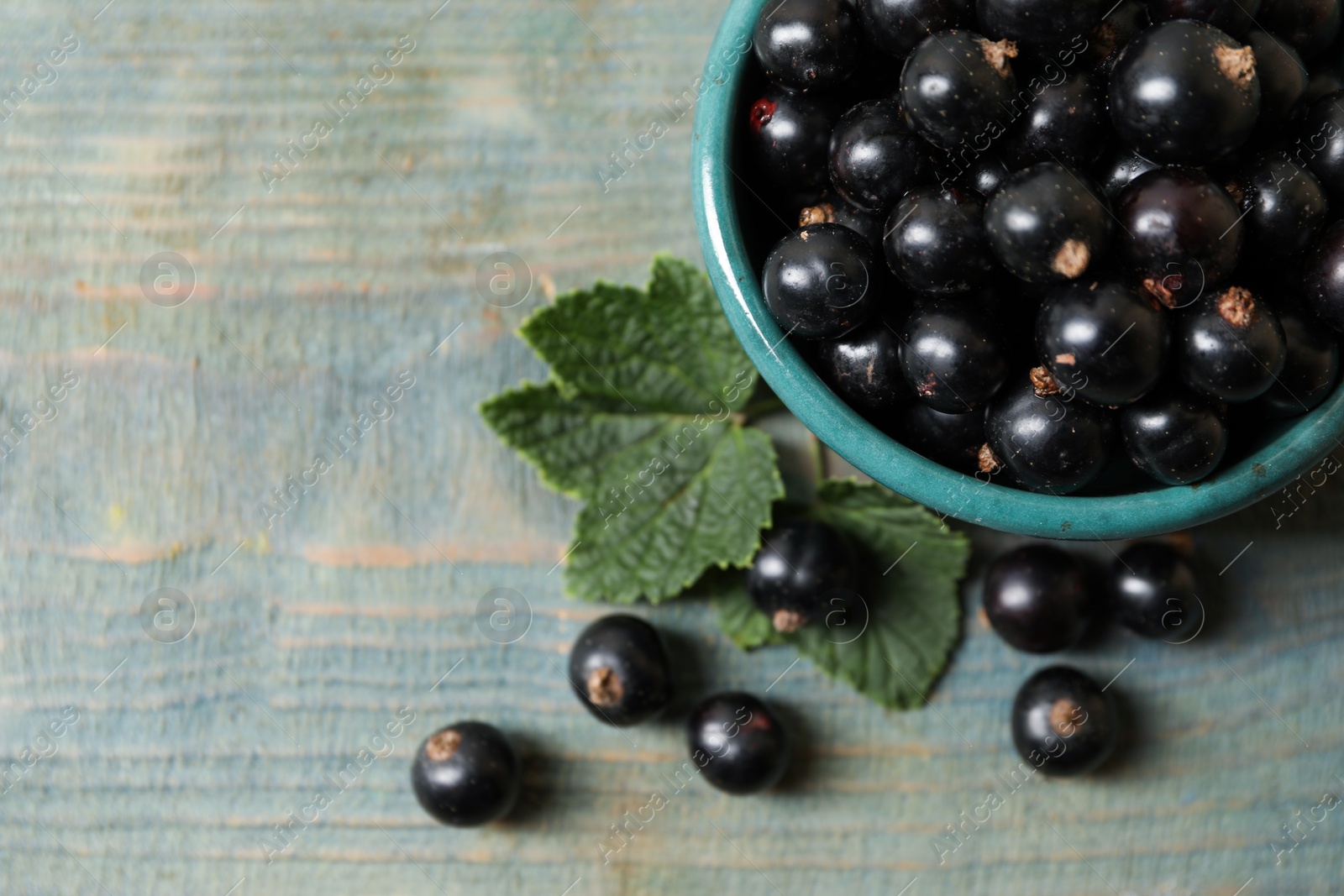 Photo of Ripe blackcurrants and leaves on wooden rustic table, flat lay. Space for text