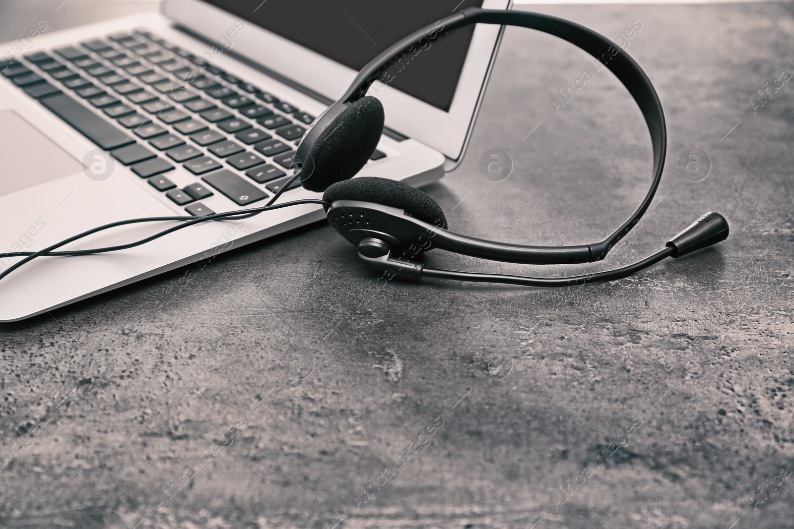 Photo of Modern laptop and headset on table. Technical support concept