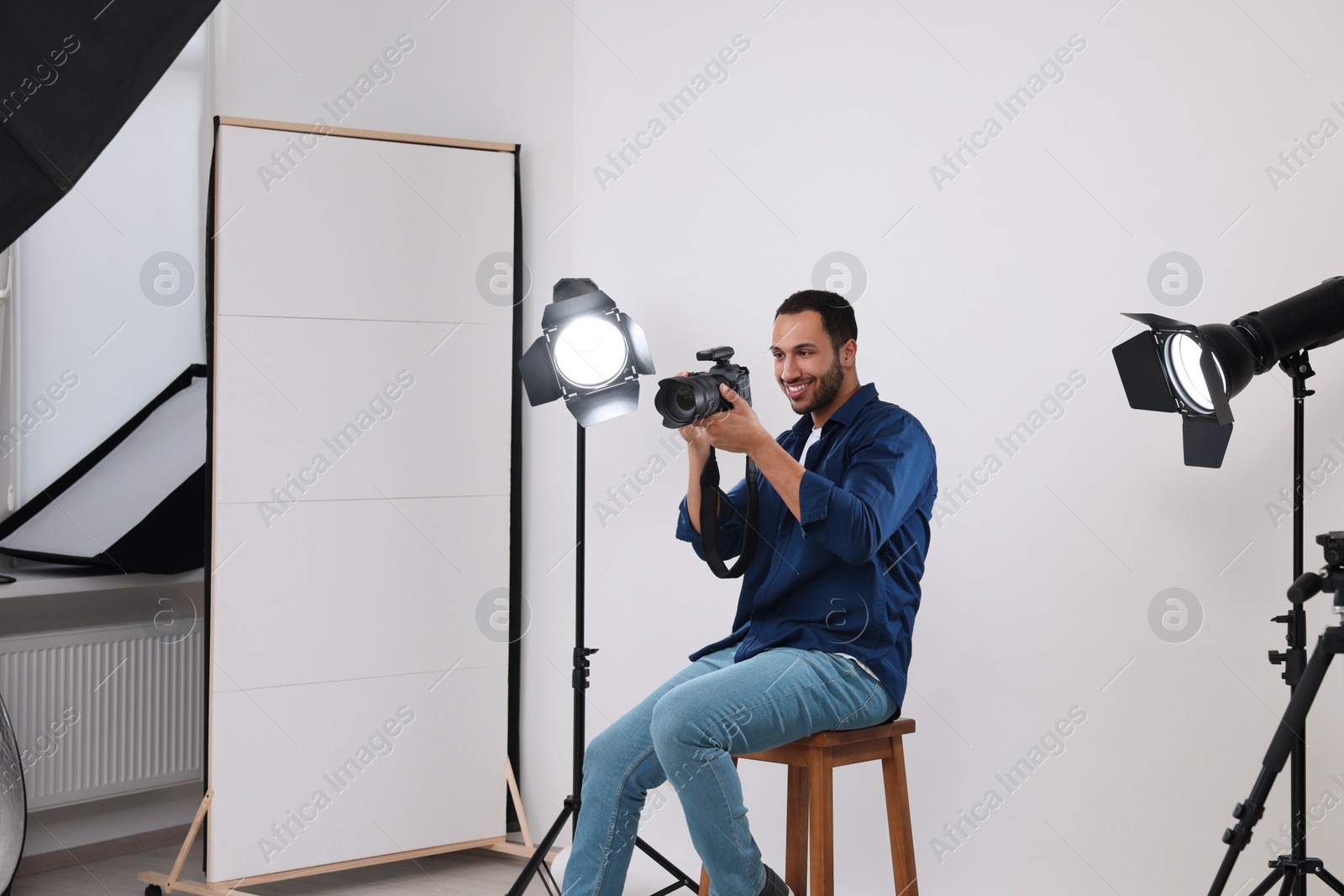 Photo of Young professional photographer with camera in modern photo studio