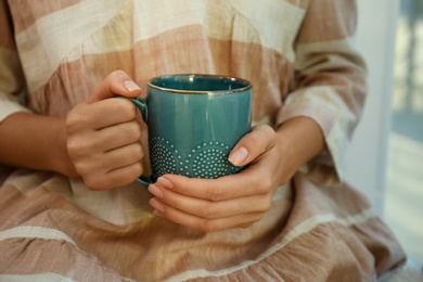 Photo of Woman holding elegant cup indoors, closeup view