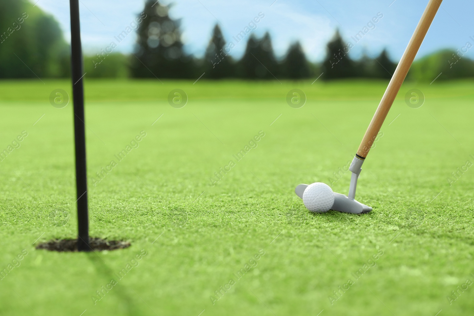 Photo of Hitting golf ball with club on green course