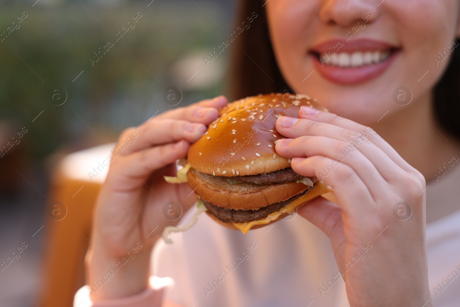 Photo of Lviv, Ukraine - September 26, 2023: Woman eating McDonald's burger outdoors, closeup. Space for text