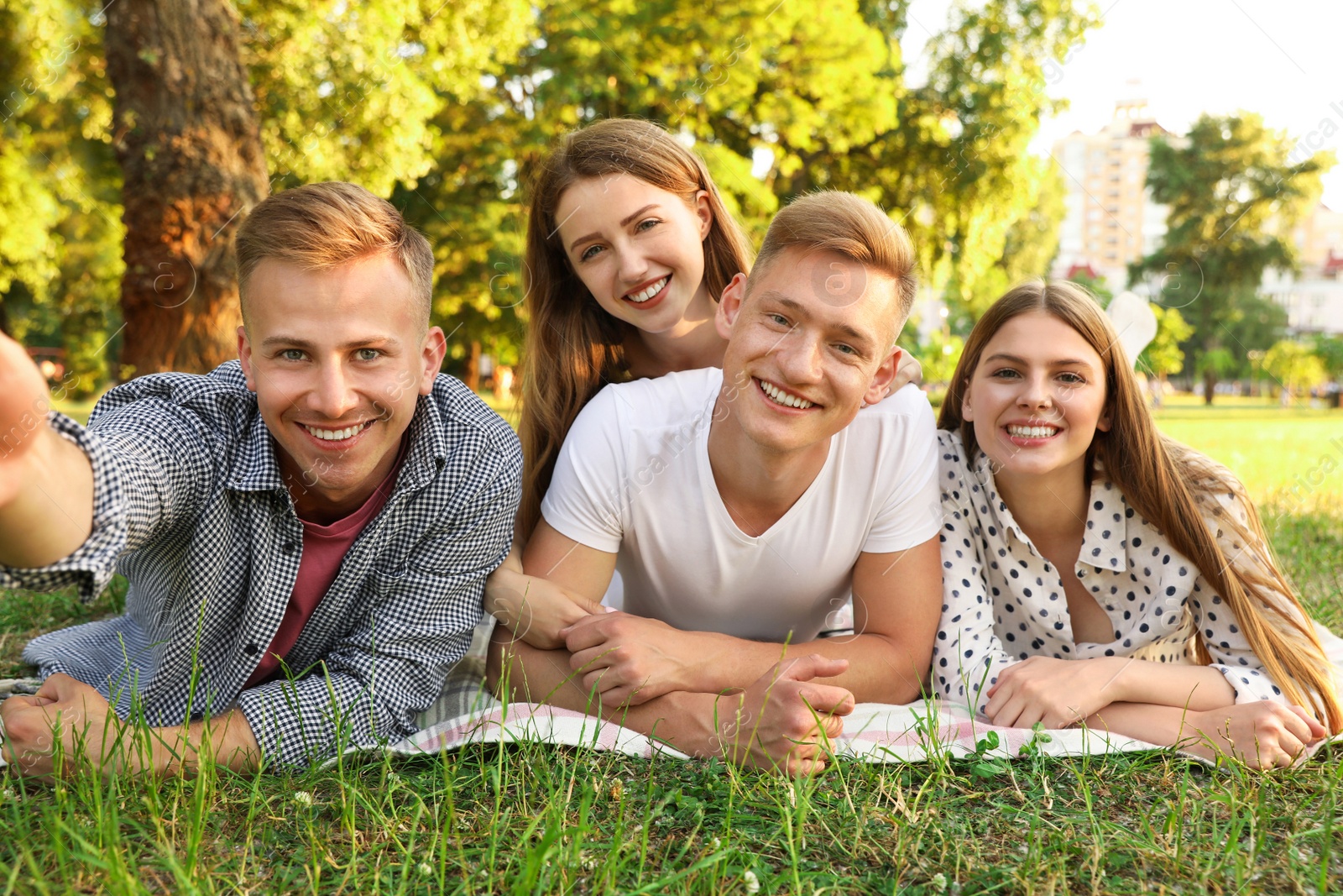 Photo of Young people taking selfie while having picnic in park on summer day