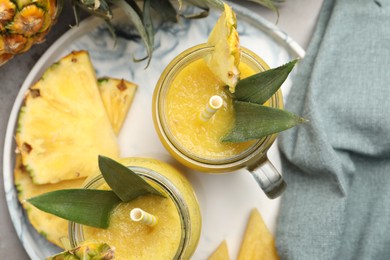 Photo of Tray with tasty pineapple smoothie and sliced fruit on table, flat lay