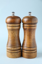 Photo of Wooden salt and pepper shakers on light background, closeup