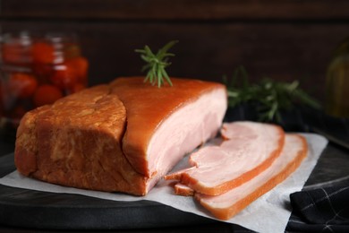 Photo of Delicious smoked bacon with rosemary on board, closeup