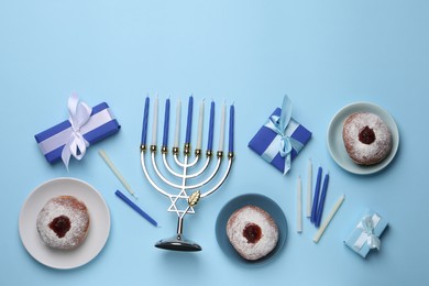 Flat lay composition with Hanukkah menorah and donuts on light blue background